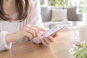 テーブルでスマートフォンを操作する女性の手元のイメージ