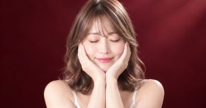 ワインレッドの背景の中で、穏やかにほほえむ様子のイメージ