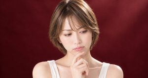 ワインレッドの背景の中で、悩みを抱えて考える様子のイメージ