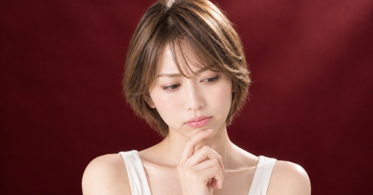 ワインレッドの背景の中で、悩みを抱えて考える様子のイメージ